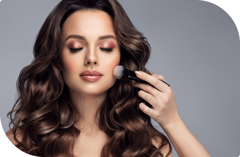 Woman applying makeup with brush, flawless skin and curls.