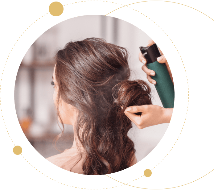 Woman applying hairspray to styled brunette hair.